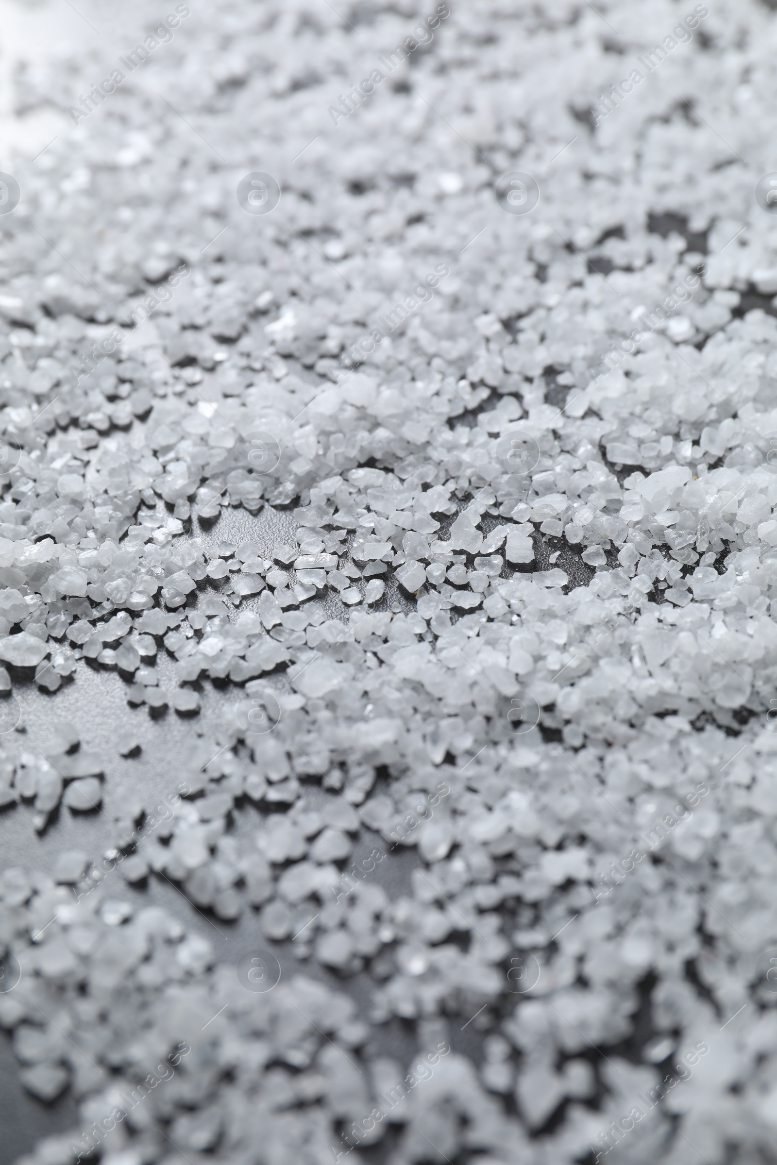 Photo of Scattered natural salt on black table, closeup