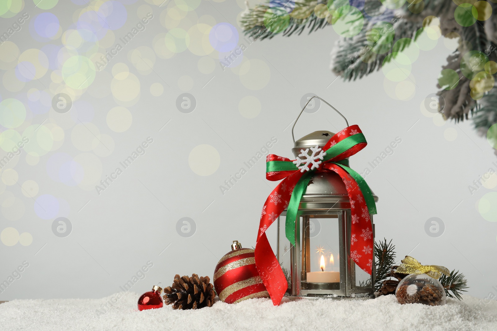 Photo of Decorative lantern and Christmas decor on snow against festive lights. Space for text