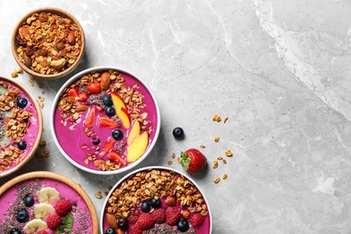 Acai smoothie bowls with granola and berries on marble table, flat lay. Space for text