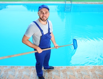 Photo of Male worker cleaning outdoor pool with scoop net