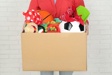 Woman holding box of unwanted stuff indoors, closeup