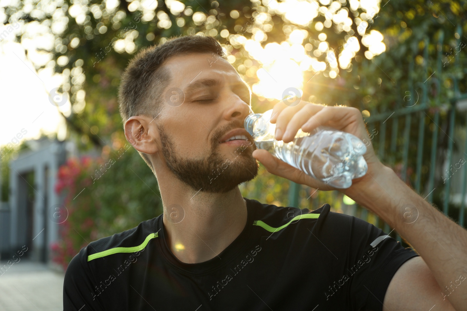 Photo of Man drinking water outdoors on hot summer day. Refreshing drink