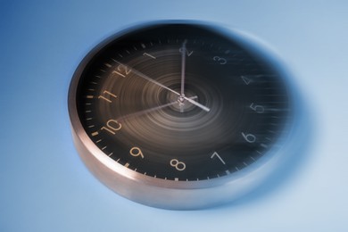 Image of Fleeting time concept. Clock on light blue background, motion effect