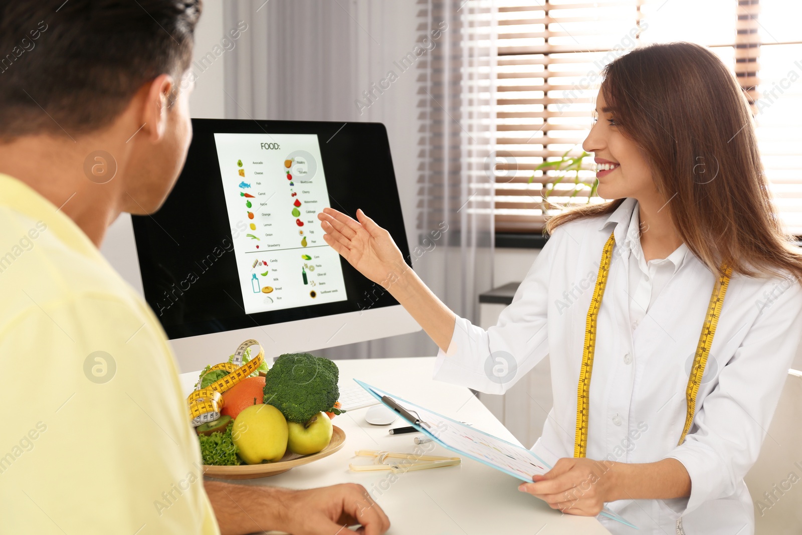 Photo of Young nutritionist consulting patient at table in clinic