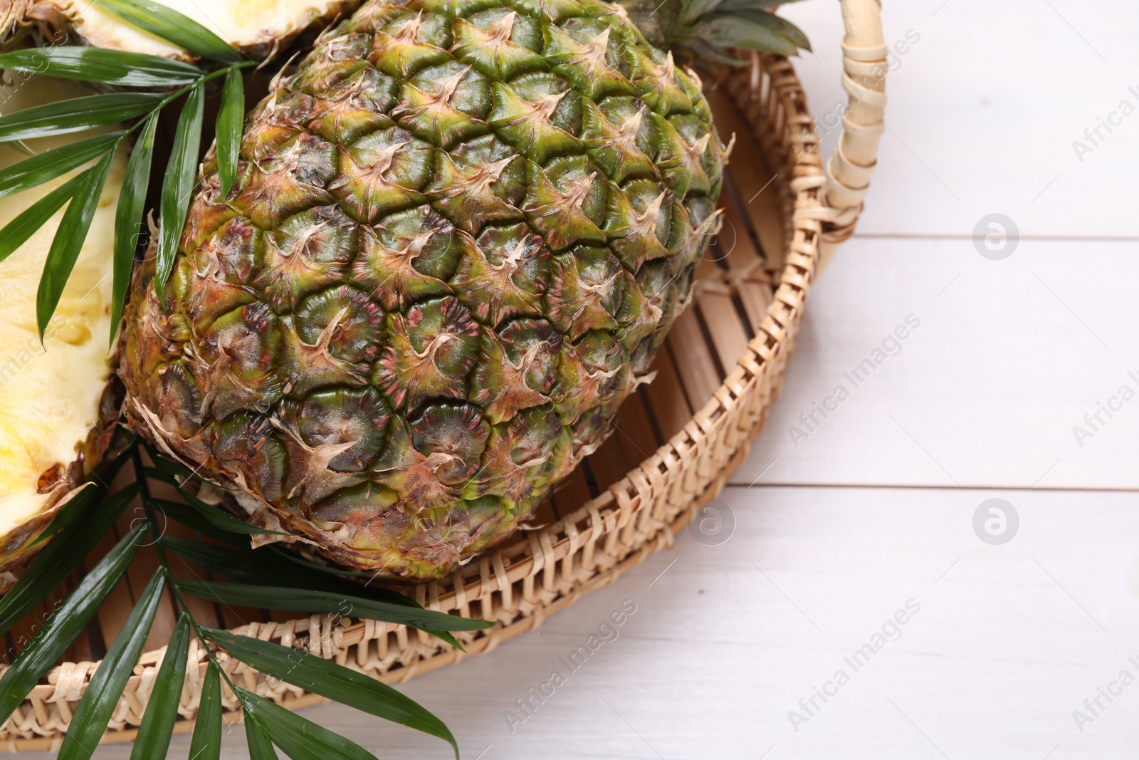 Photo of Whole and cut ripe pineapples on white wooden table, space for text