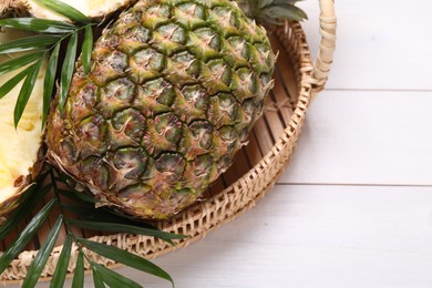 Photo of Whole and cut ripe pineapples on white wooden table, space for text