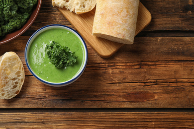 Photo of Tasty kale soup on wooden table, flat lay. Space for text