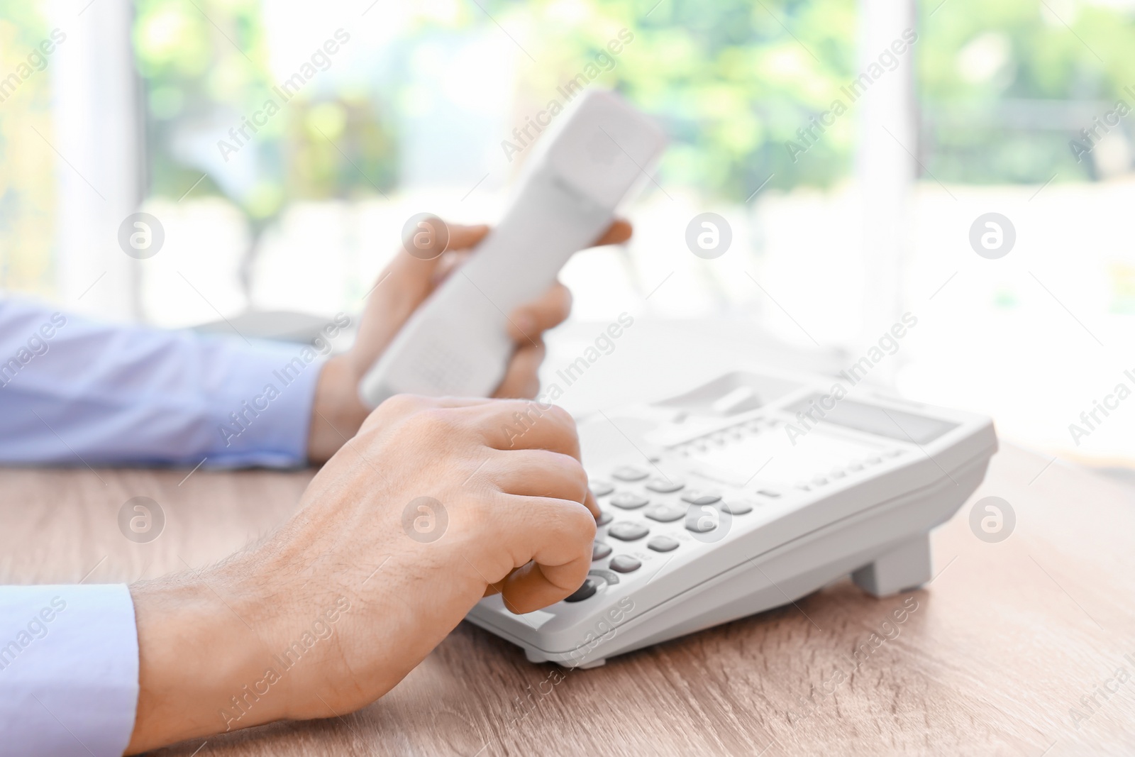 Photo of Man dialing number on telephone at workplace