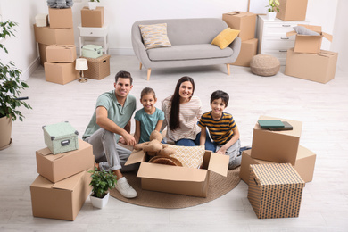 Happy family unpacking moving boxes at their new home