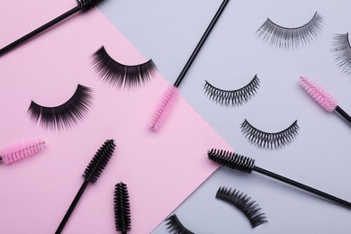 Flat lay composition with fake eyelashes and brushes on color background