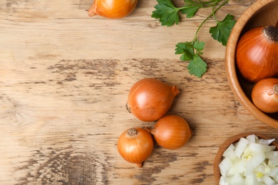 Photo of Fresh ripe onions on wooden table, top view