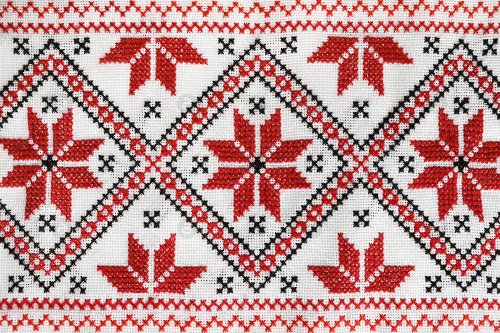 Photo of Traditional Ukrainian embroidery on white canvas as background, closeup. National handicraft