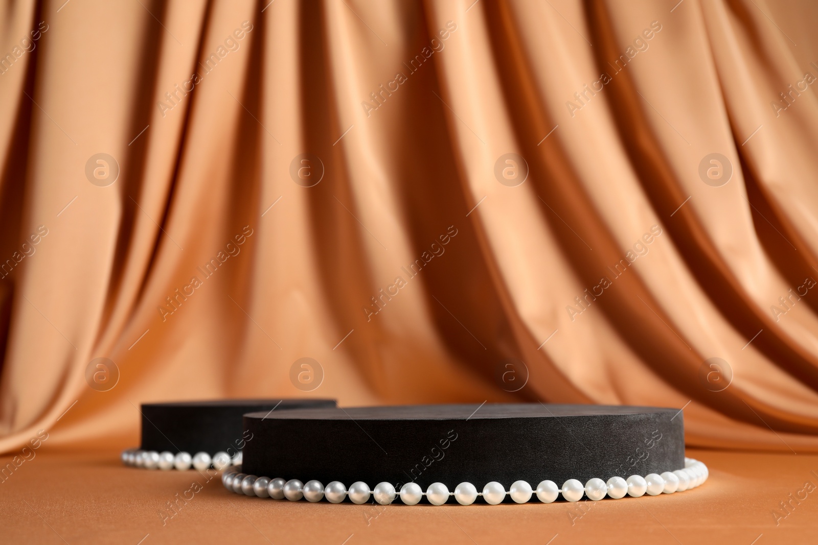 Photo of Black geometric figures and pearls on light brown table, space for text. Stylish presentation for product