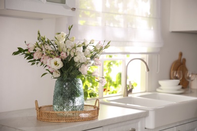 Photo of Bouquet of beautiful flowers on countertop in kitchen, space for text. Interior design