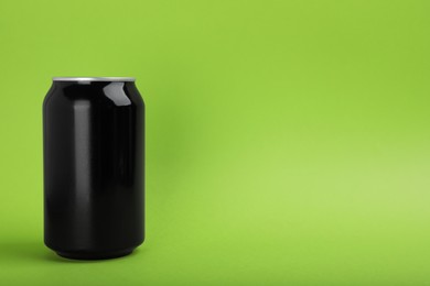 Black can of energy drink on green background. Space for text