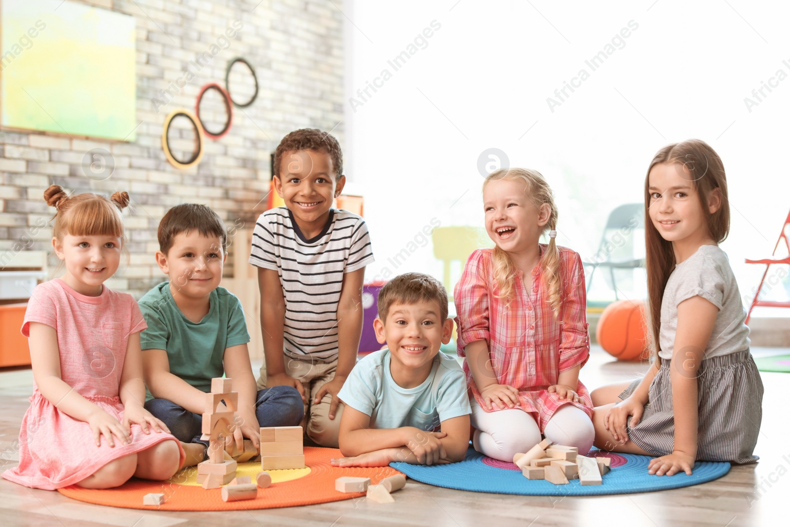 Photo of Cute little children playing with wooden blocks indoors