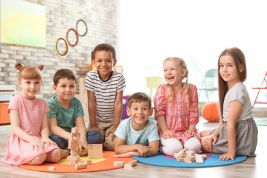 Photo of Cute little children playing with wooden blocks indoors