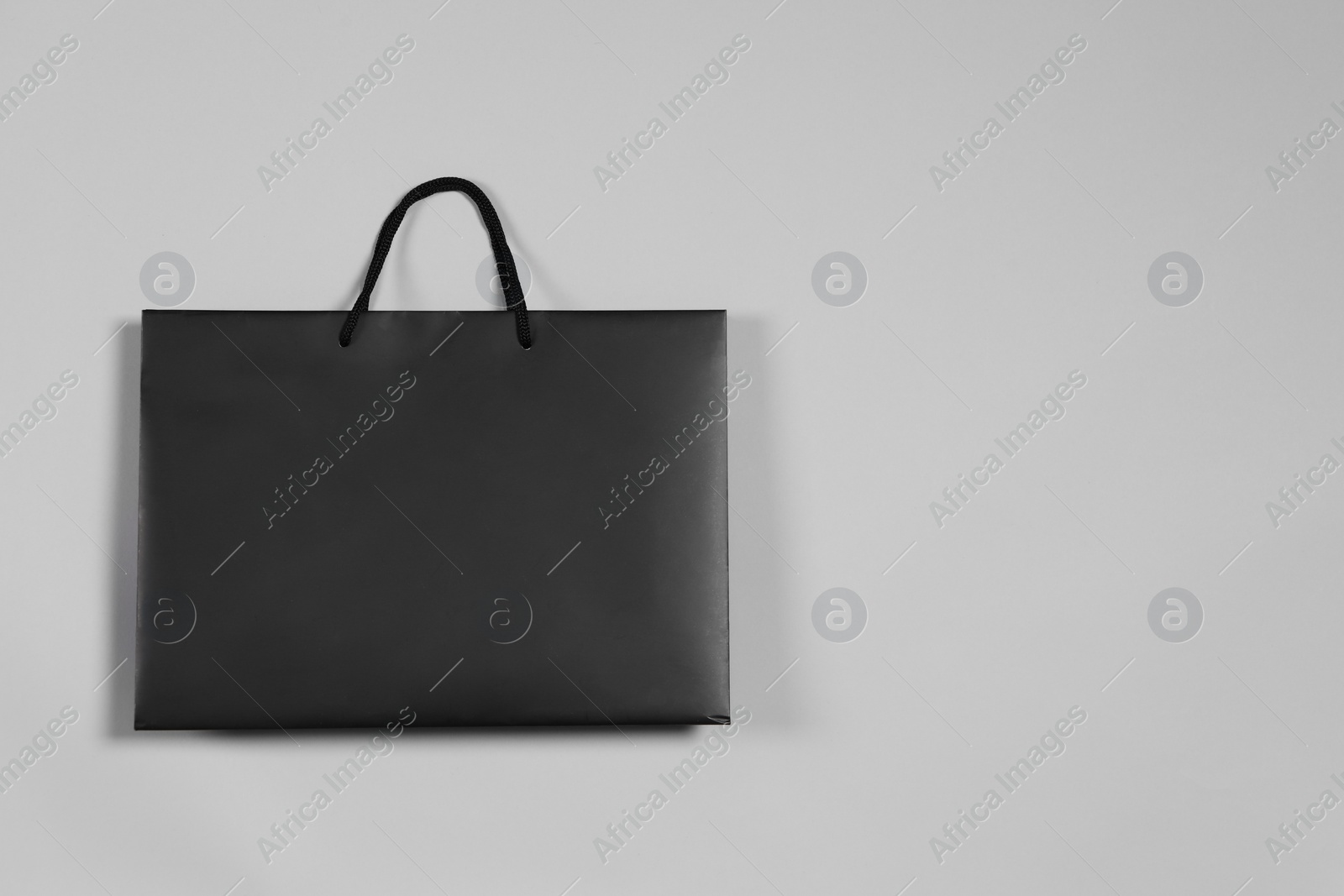 Photo of One black paper shopping bag on grey background, top view. Space for text