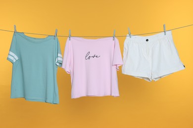 Different clothes drying on laundry line against orange background