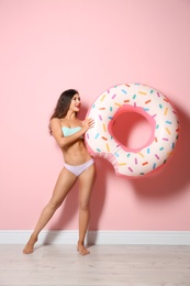 Beautiful young woman with inflatable ring near color wall