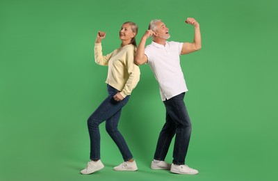 Photo of Senior couple dancing together on green background