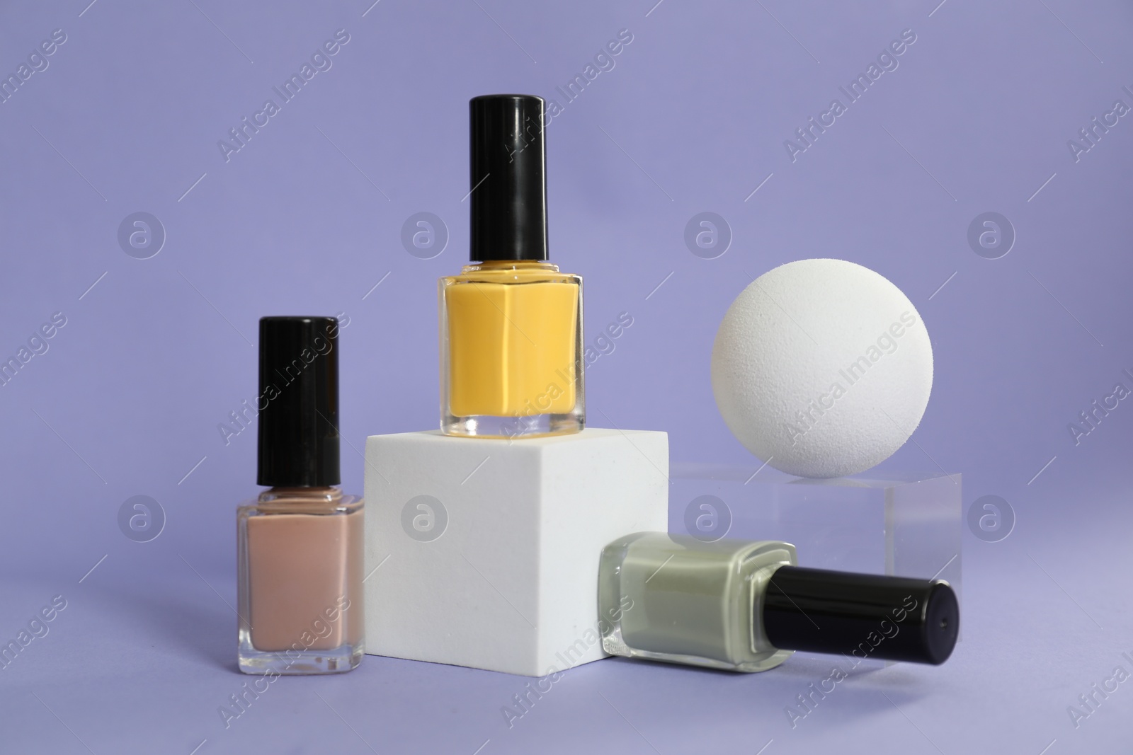 Photo of Stylish presentation of nail polishes on lilac background