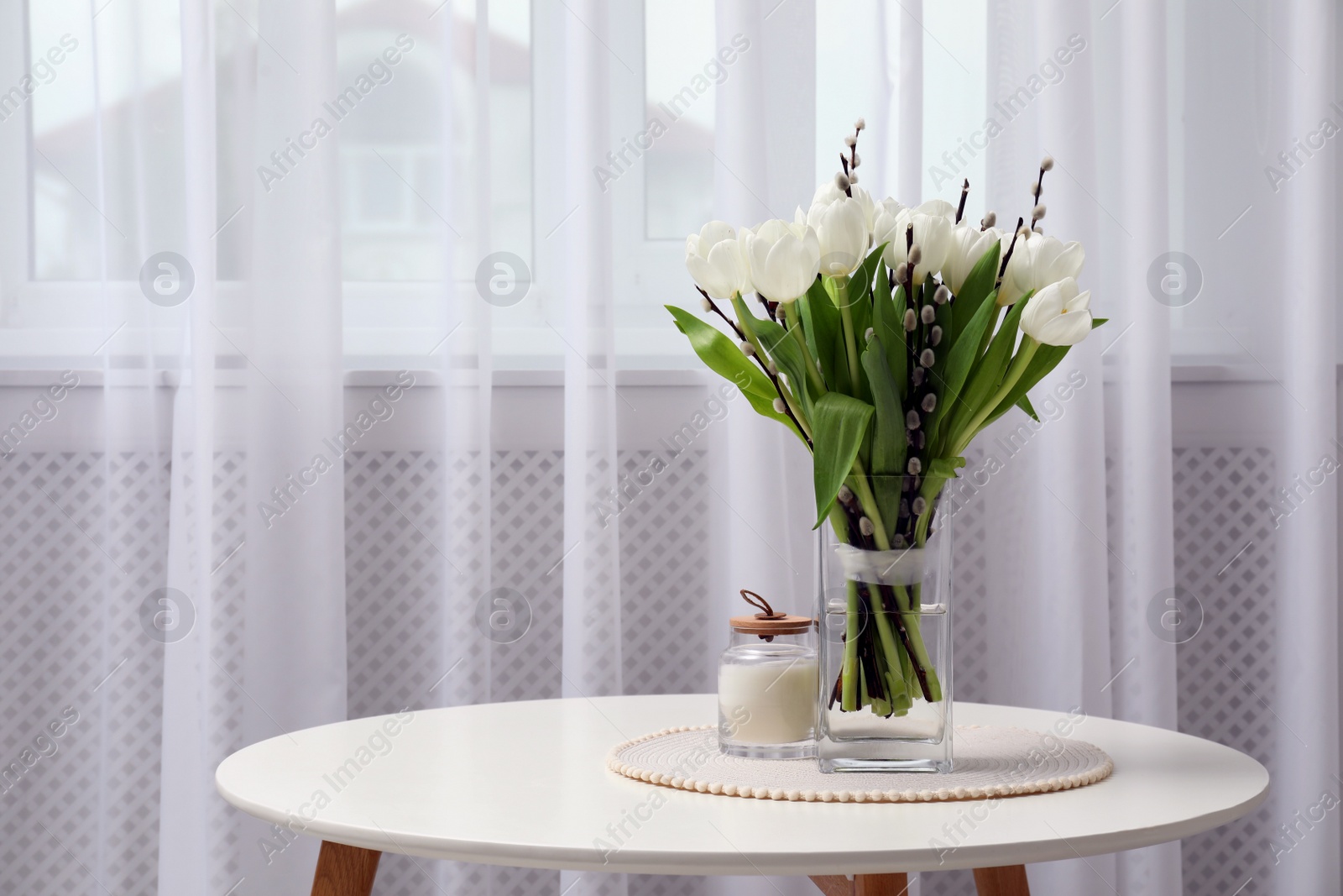 Photo of Beautiful bouquet of willow branches and tulips in vase on table indoors, space for text