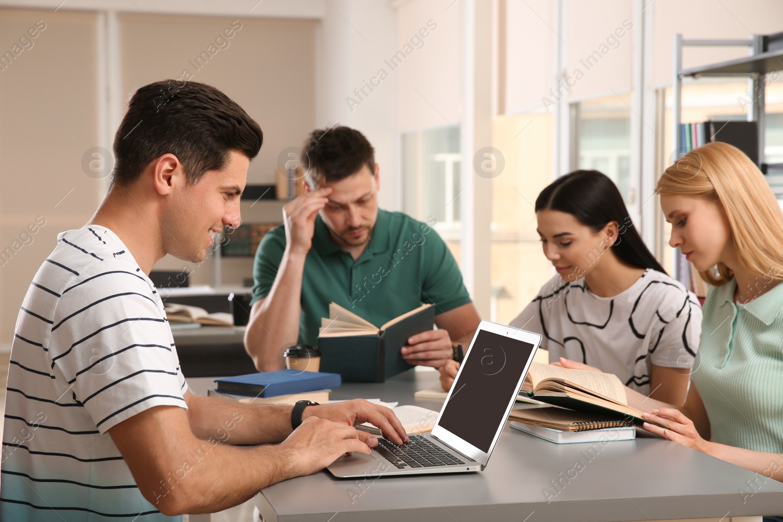 Photo of Young people discussing group project at table in library