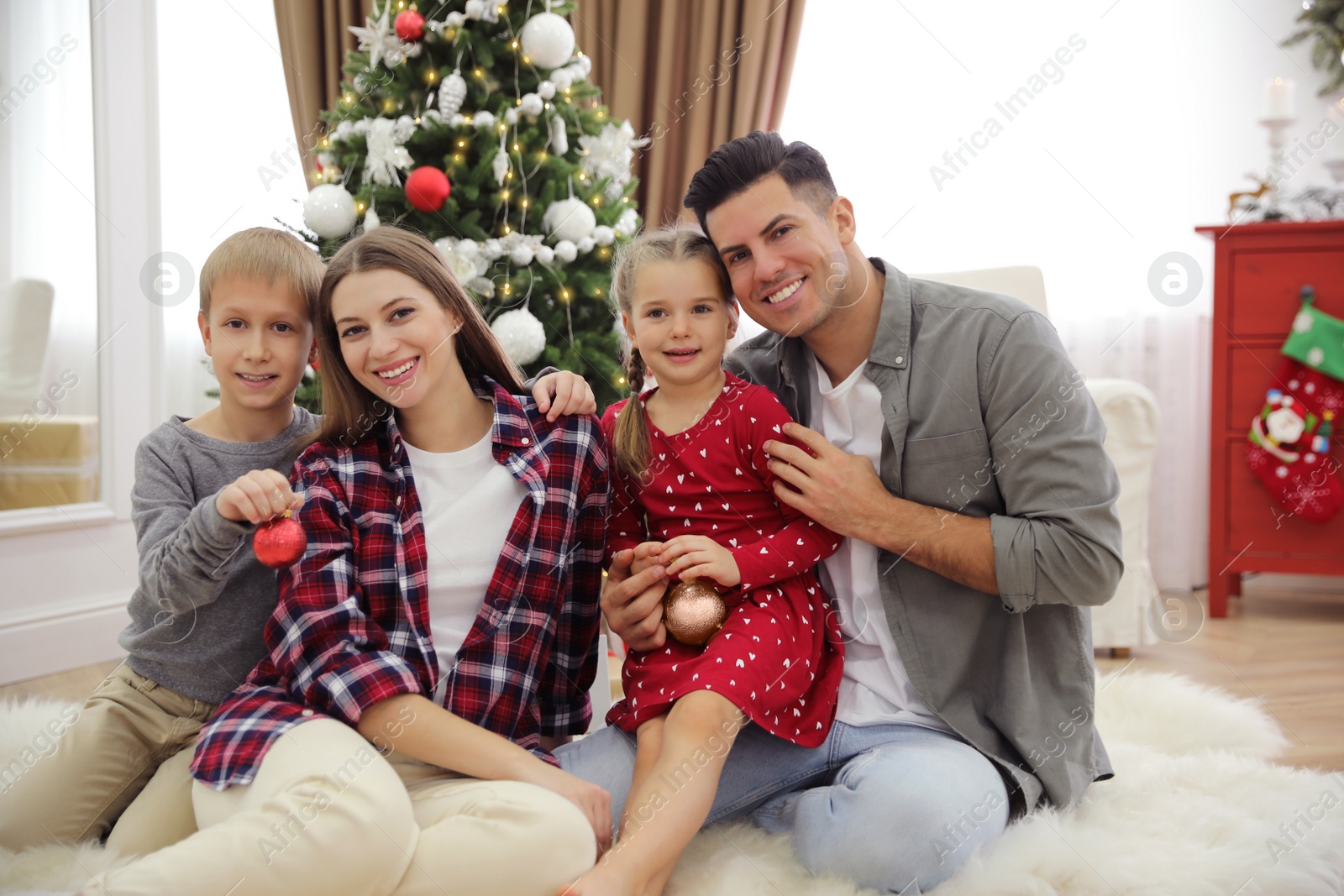 Photo of Happy family with cute children near Christmas tree together at home