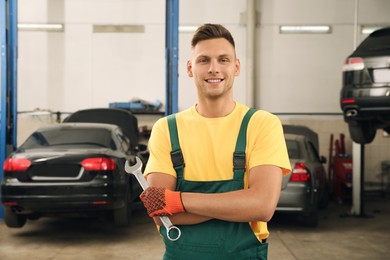 Portrait of professional mechanic with wrench at automobile repair shop