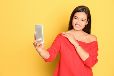Photo of Young beautiful woman taking selfie against color background