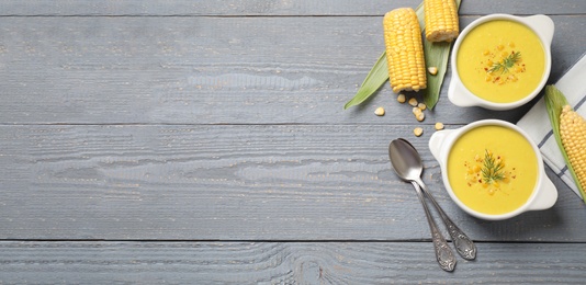 Photo of Delicious creamy corn soup served on grey wooden table, flat lay. Space for text