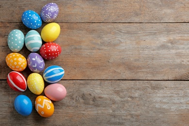 Flat lay composition of painted Easter eggs on wooden table, space for text