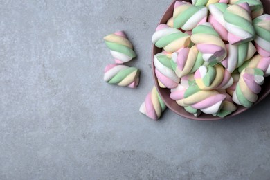 Photo of Bowl with colorful marshmallows on grey table, flat lay. Space for text