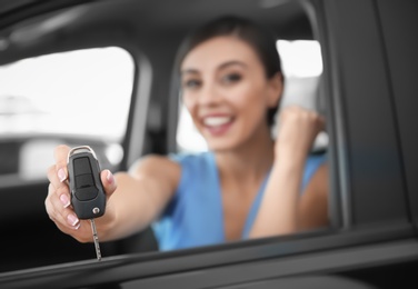Photo of Young woman with key sitting in driver's seat of new car, closeup
