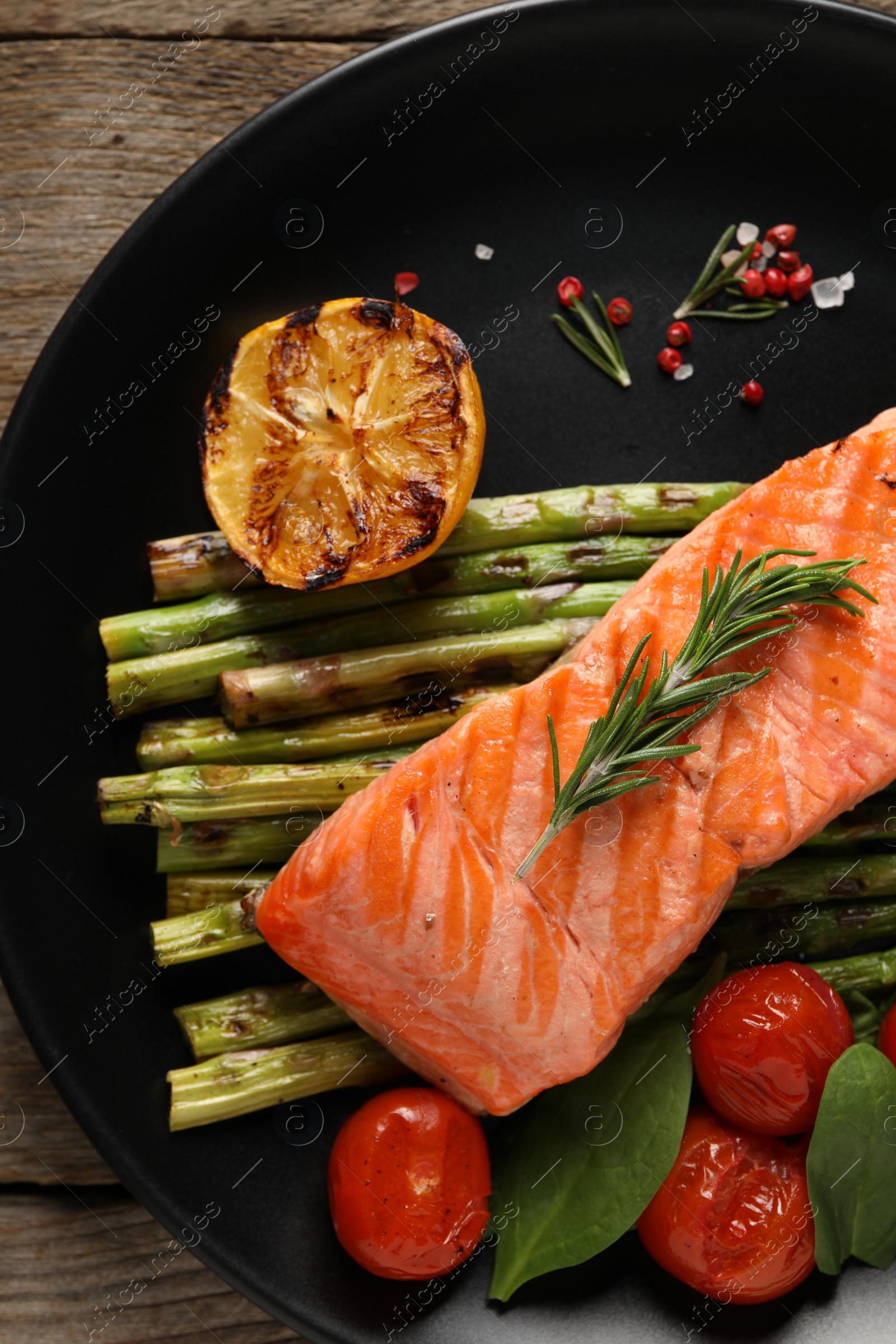 Photo of Tasty grilled salmon with tomatoes, asparagus and spices on plate, top view