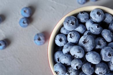 Photo of Crockery with juicy and fresh blueberries on color table, top view
