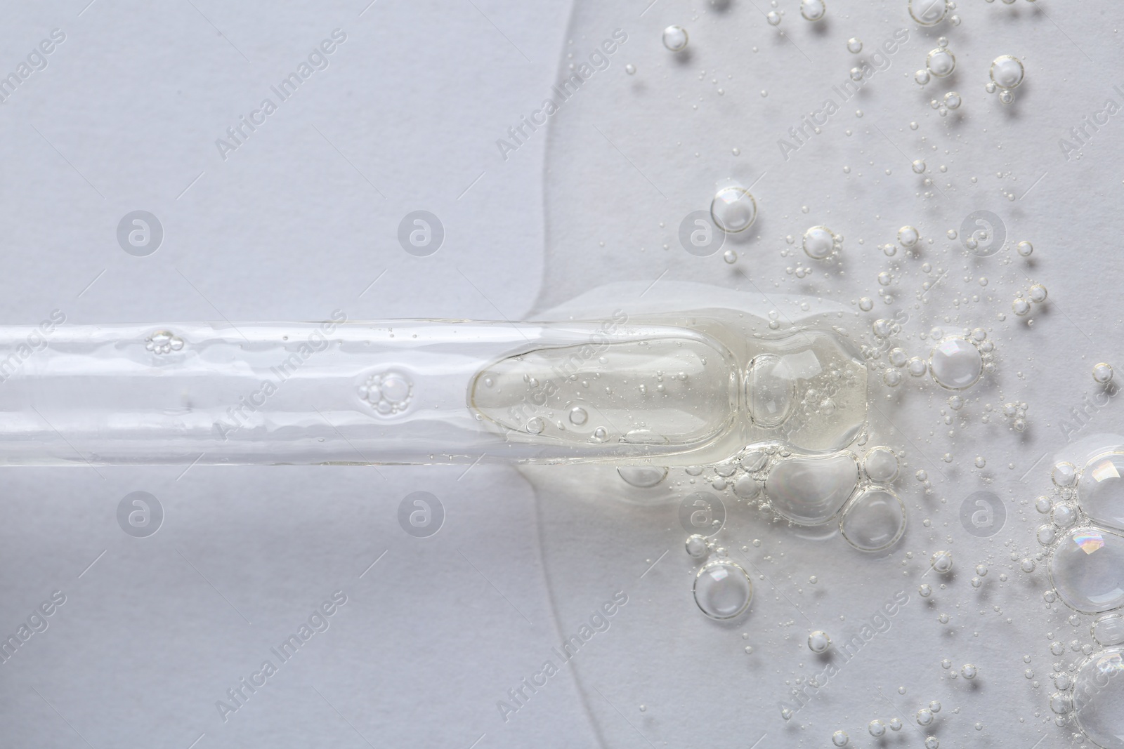 Photo of Pipette with cosmetic serum on white background, macro view