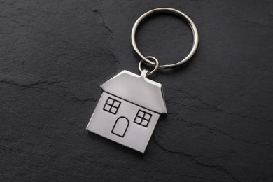 Metallic keychain in shape of house on black background, above view