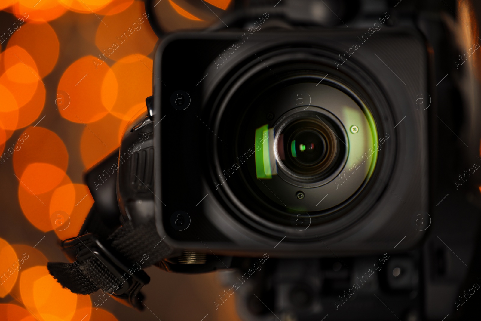 Photo of Modern video camera against blurred lights, closeup