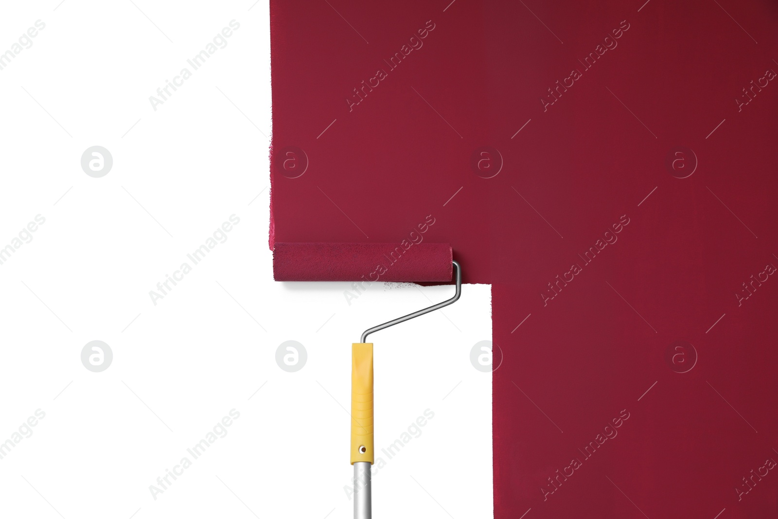 Photo of Applying burgundy paint with roller brush on white wall