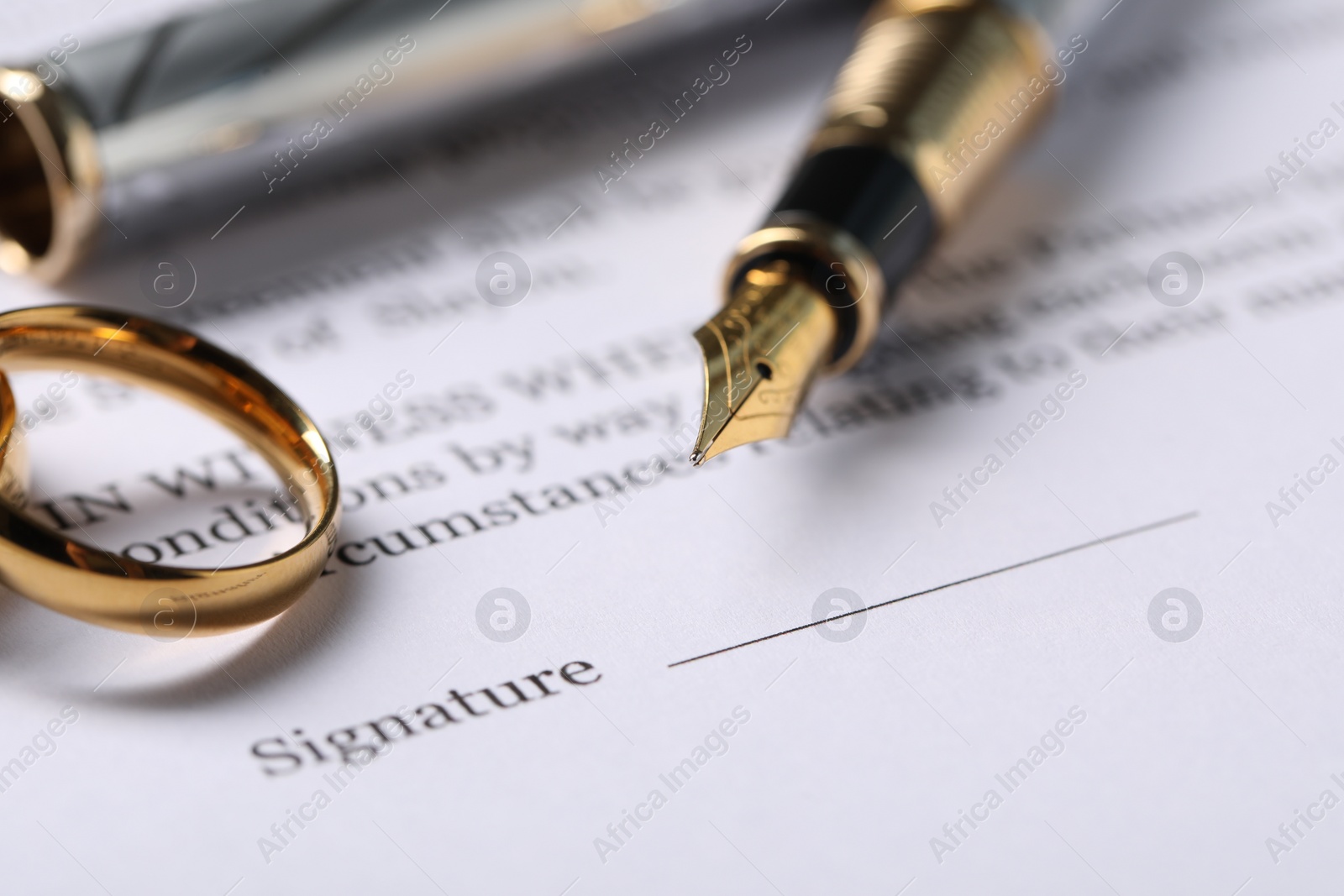 Photo of Marriage contract, gold rings and pen on table, closeup