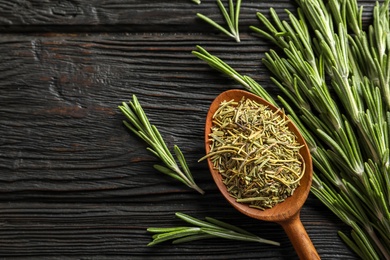 Photo of Spoon with dried rosemary and twigs on wooden table, top view