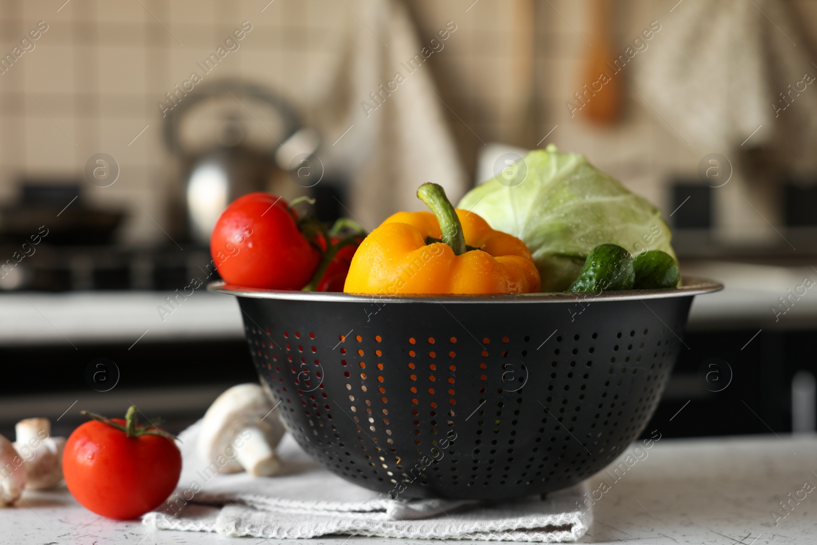 Photo of Metal colander with different wet vegetables on white textured table