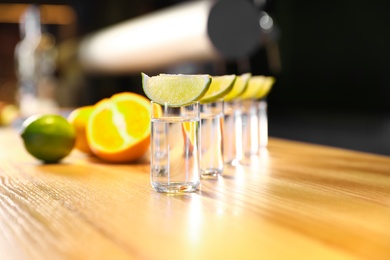 Photo of Vodka shots and lime slices on wooden bar counter