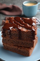 Photo of Delicious chocolate brownies with sweet syrup served on table, closeup