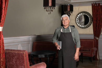 Photo of Senior business owner with tablet in his restaurant