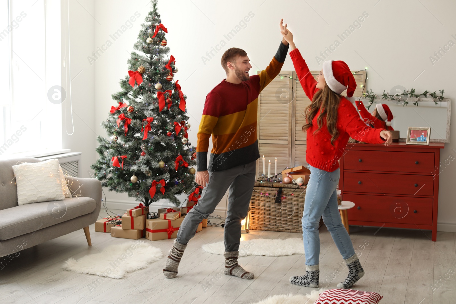 Photo of Happy young couple dancing near Christmas tree at home