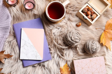 Photo of Flat lay composition with notebooks, cup of tea and wool balls on fuzzy rug