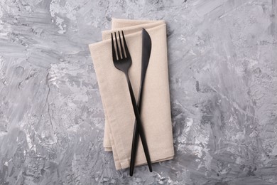 Photo of Elegant cutlery and kitchen towel on grey textured table, top view